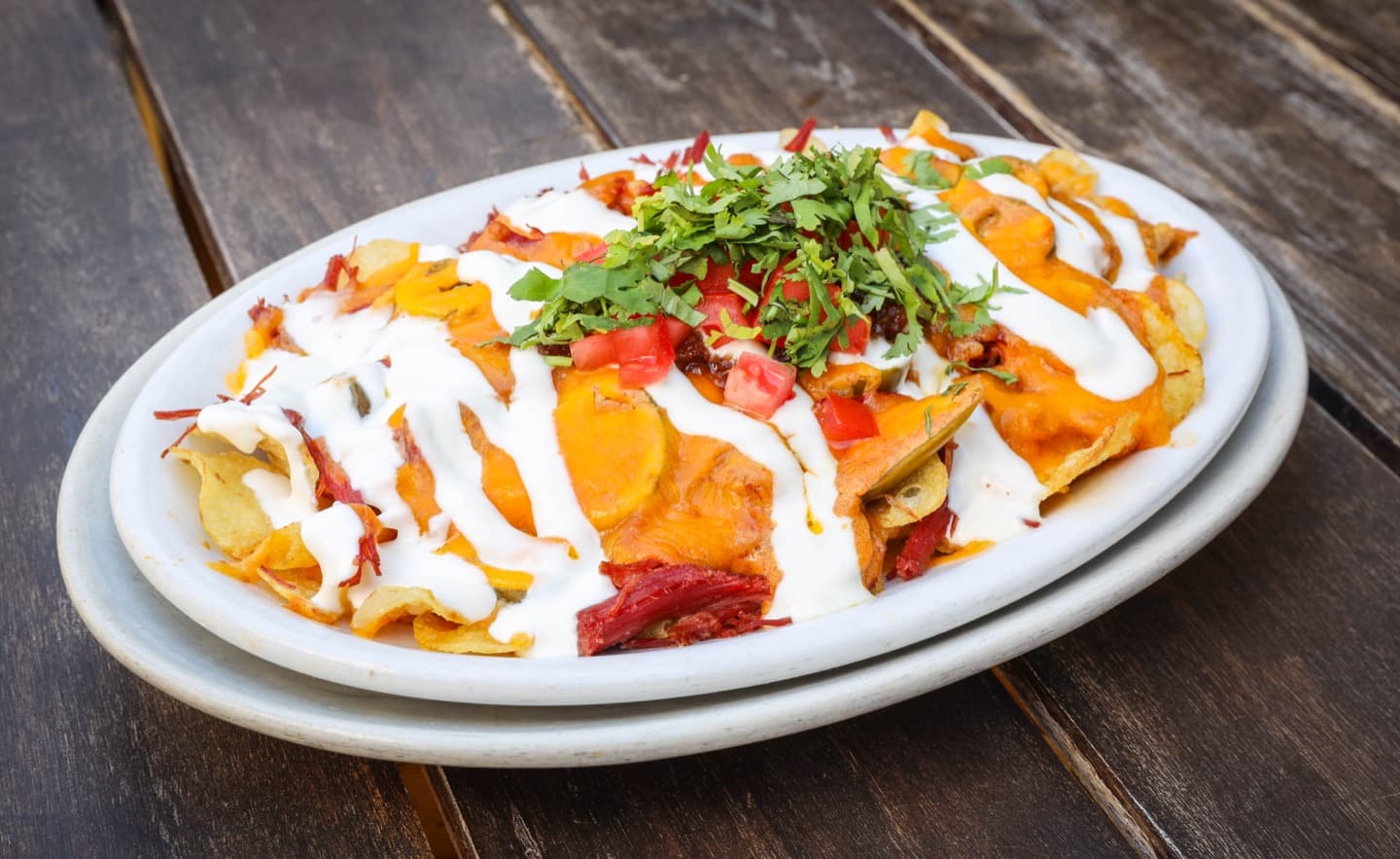 Loaded Irish nachos with cheddar, tomatoes, herbs, and sour cream