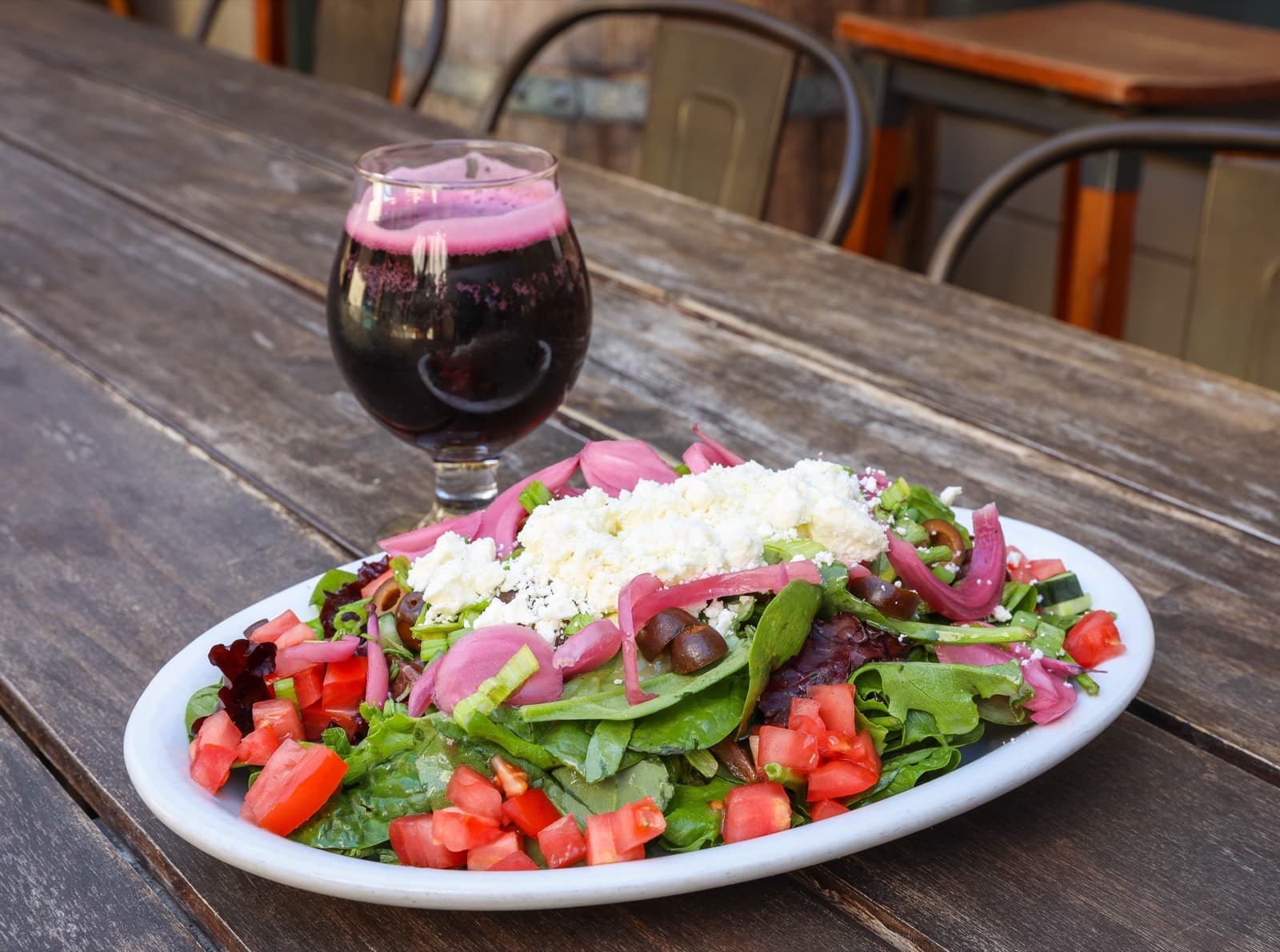 Mixed green salad with feta, olives, tomatoes, and pickled onions