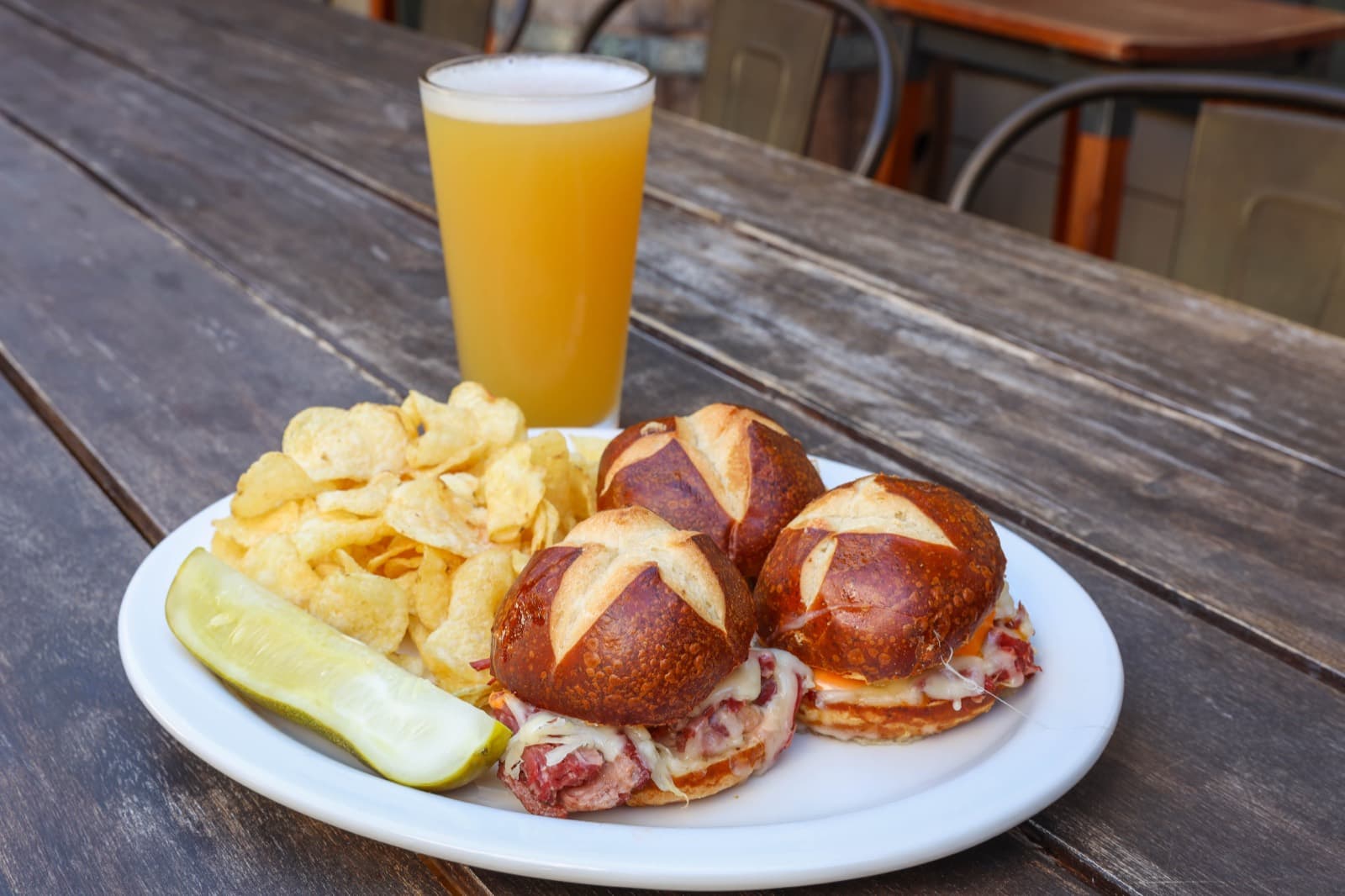 Pretzel bun sliders served with chips and a pickle